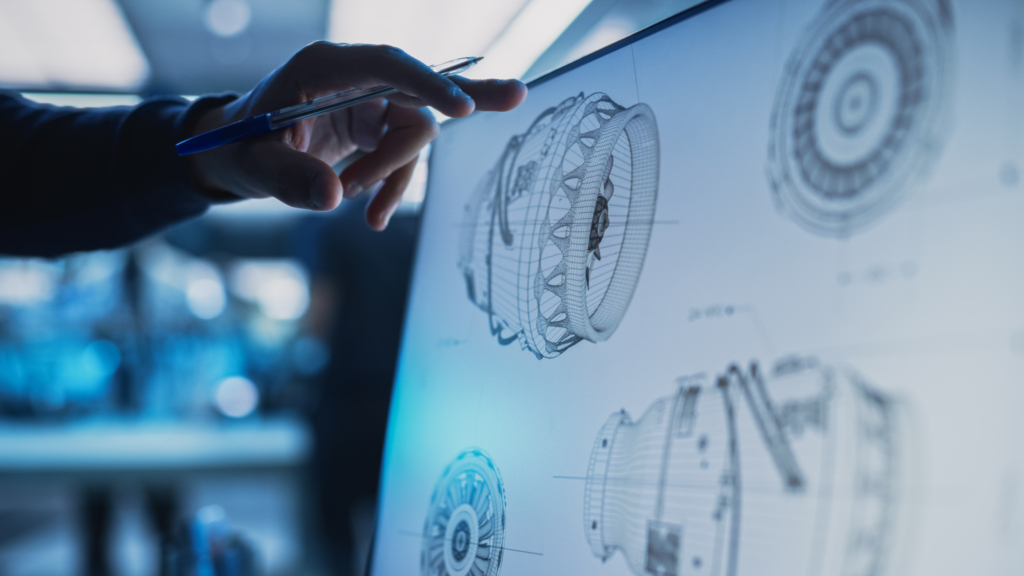 Close Up of a Desktop Computer Monitor Screen with 3D CAD Software with Prototype Jet Engine Project. Specialist Discussing Work, His Hand Visible In Front of the Screen.
